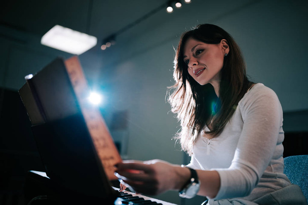 Image of a female pianist turning the sheet music while playing. - Foto, imagen
