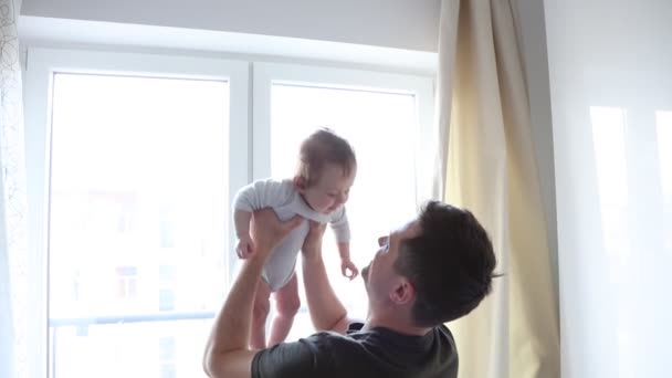 Νεαρός πατέρας παίζει με τον μικρό γιο του στέκεται στο παράθυρο - Πλάνα, βίντεο