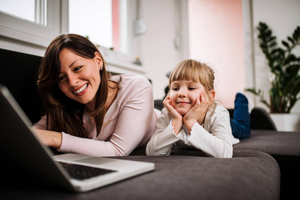 Mother and daughter enjoying free time at home. Watching cartoons with daughter. - Fotoğraf, Görsel