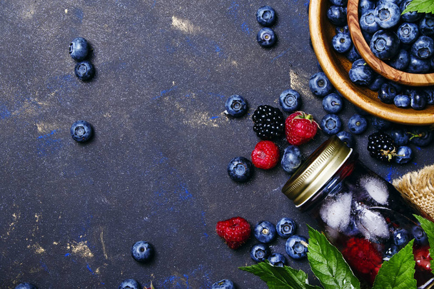 Summer ice berry tea with blueberries, raspberries, blackberries and ice, top view - Foto, immagini