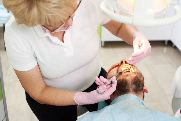 Zahnärztin macht Betäubungsspritze im Mund einer Patientin. Injektionstechniken zur Narkose des Zahnes in der modernen Zahnklinik - Foto, Bild