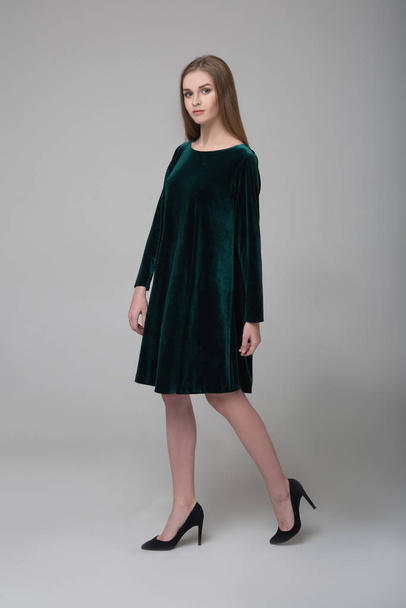Young beautiful long-haired female model in dark green short dress - Photo, Image