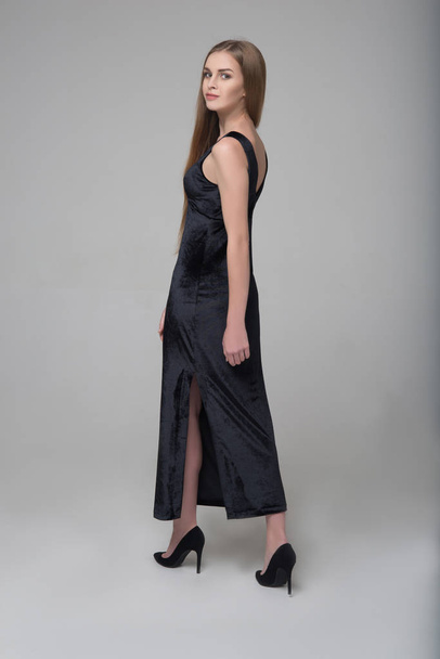 Jovem bela modelo feminino de cabelos longos caminha em vestido preto
 - Foto, Imagem