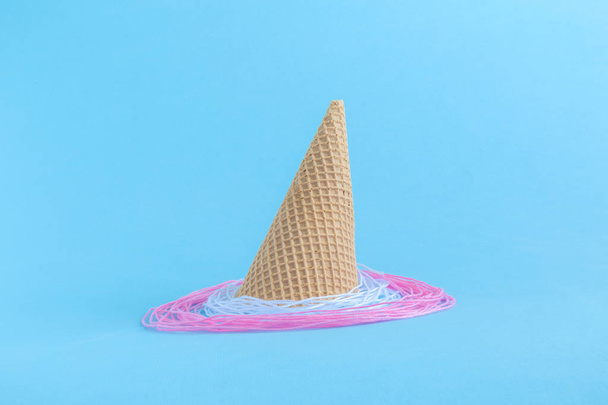 Ice cream cone with whipped cream made of strings isolated on blue. - Foto, Imagem