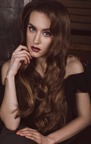 Portrait of an attractive brown-haired woman with a hair style in a Hollywood wave style, in a black dress with open shoulders.  - Foto, imagen