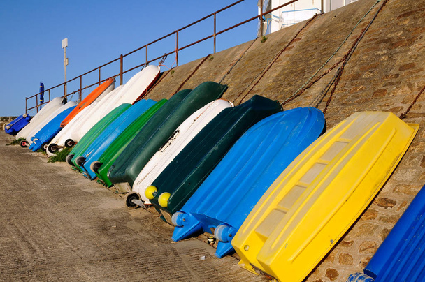 Многоцветные небольшие лодки, стоящие напротив стены в порту Мария в Кибероне в департаменте Морбиан в Бретани на северо-западе Франции
. - Фото, изображение