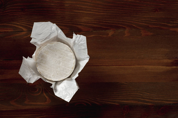 close-up of delicious white Camembert cheese on wooden table background - Fotó, kép
