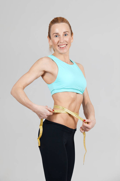 atlética mujer delgada que mide el tamaño de su cintura por la cinta de la regla
  - Foto, Imagen