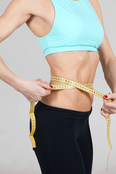 mulher atlética magro medindo o tamanho de sua cintura pela fita régua
  - Foto, Imagem