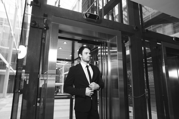 бізнесмен середнього віку з портфелем, що виходить з ліфта
 - Фото, зображення