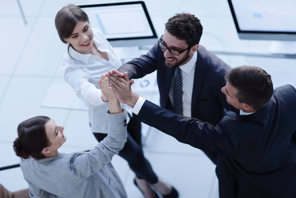successful business team giving each other a high-five, standing in the office - Photo, Image