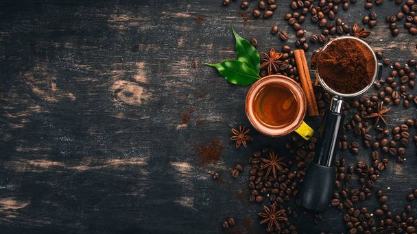 Hot espresso coffee in a cup. Cinnamon. On a black wooden background. Top view. Copy space. - Foto, imagen