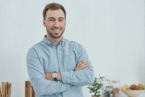 portrait of smiling man with arms crossed looking at camera at home - Photo, Image