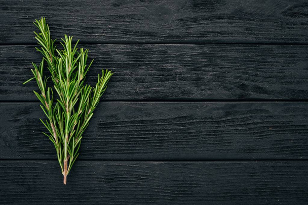 Rosemary. On a black wooden background. Top view. Copy space. - Фото, изображение