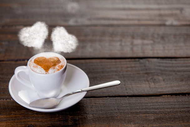 Bílý šálek kávy se lžičkou a srdíčka dva páry na dřevěný stůl - Fotografie, Obrázek