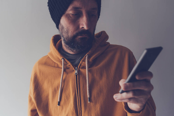 Casual adult male with cap looking at mobile phone - Photo, Image
