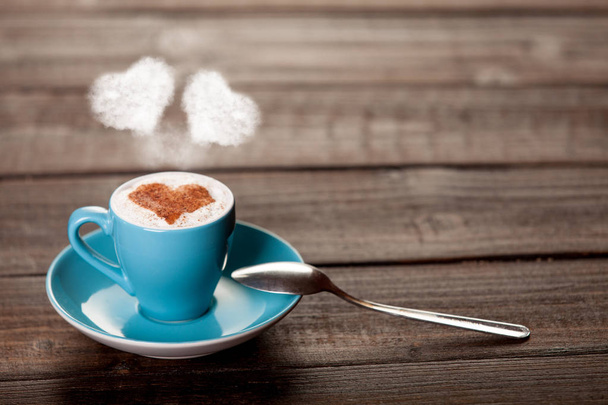 Sininen kuppi kahvia kaksi sydämen muotoisia höyry puinen pöytä
 - Valokuva, kuva
