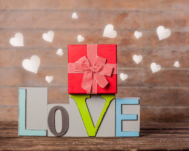 Texte amour et boîte cadeau avec des cœurs autour sur fond en bois
  - Photo, image
