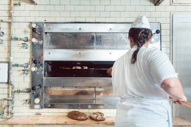 Panadero conseguir pan fresco con pala fuera del horno
 - Foto, Imagen
