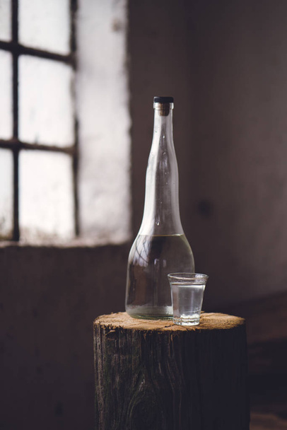 Strong alcohol drink in bottle with shot glass - 写真・画像