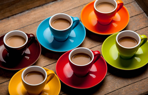 Шість барвистих чашок кави на дерев'яному фоні
  - Фото, зображення