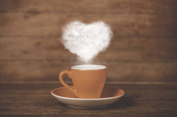 Kuppi kahvia sydämen muotoinen höyry puinen pöytä
 - Valokuva, kuva