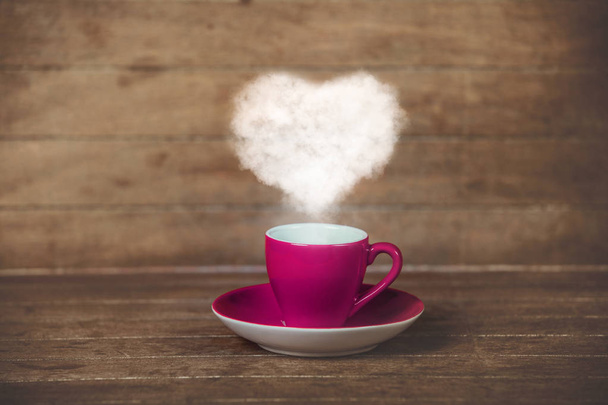 Vaaleanpunainen kuppi kahvia sydämen muotoinen höyry puinen pöytä
 - Valokuva, kuva