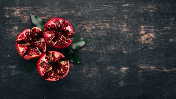 Fresh pomegranate. On a black wooden background. Top view. Copy space. - Foto, Bild