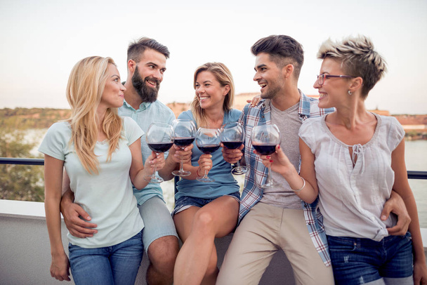 Grupo de jovens amigos se divertindo, bebendo vinho tinto e desfrutando de dias quentes de verão
. - Foto, Imagem