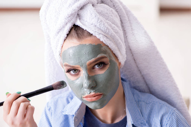 Woman applying clay mask with brush at home - Foto, afbeelding