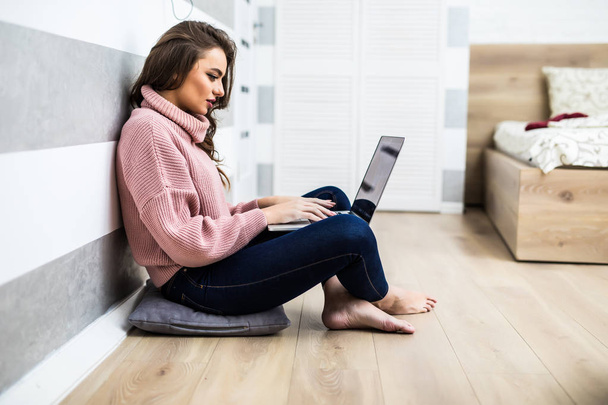 Νεαρή νεαρή γυναίκα που κάθεται στο πάτωμα με το laptop. - Φωτογραφία, εικόνα