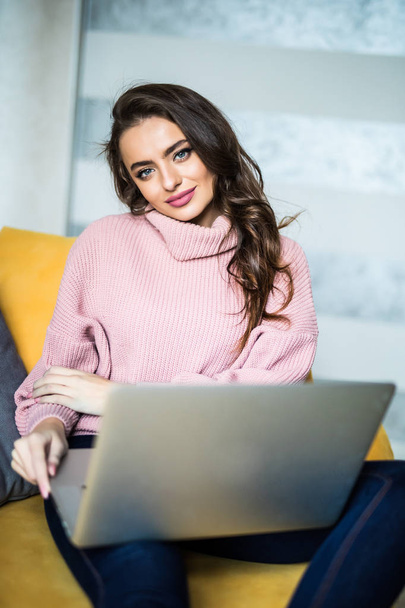 junge schöne Frau mit Laptop-Computer lächelnd glücklich beobachten und surfen oder Online-Internet-Shopping zu Hause modernes Wohnzimmer in fröhlichen und zufriedenen Gesichtsausdruck - Foto, Bild