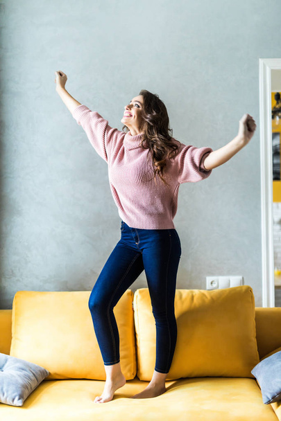 Beautiful woman jumping over the sofa at home - Foto, Imagen