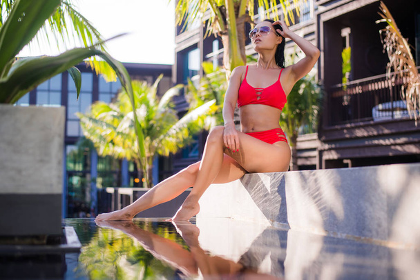 Nő: resort trópusi utazási bikini napozásra. A medence közelében fekvő gyönyörű fiatal nő. - Fotó, kép