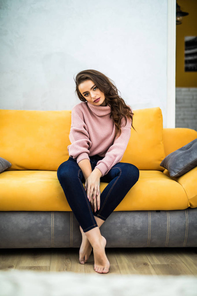 Young woman sitting on her white sofa at home - Foto, Bild