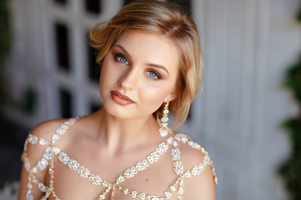 Portrait of a blond girl with blue eyes in a gold dress with jew - Foto, Imagen