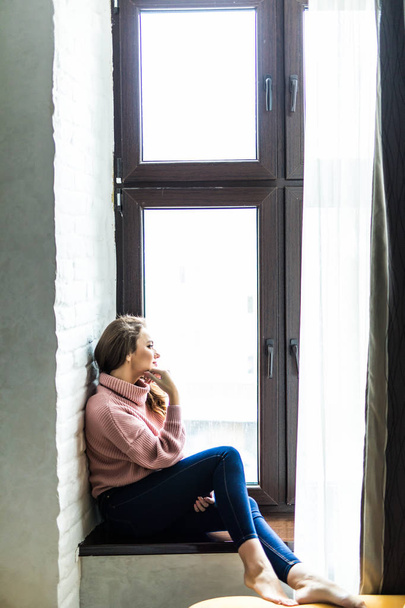 Oturan ve evde üzerinde manzarayı güzellik genç kadın - Fotoğraf, Görsel