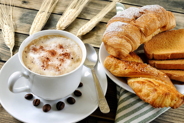 Traditioneel Italiaans ontbijt met cappuccino en croissants op een rustieke houten tafel - Foto, afbeelding