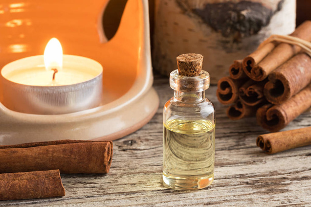 A bottle of cinnamon essential oil with cinnamon sticks - Photo, Image