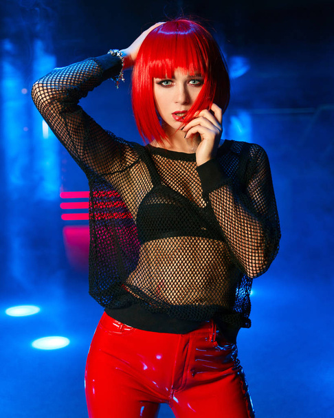 The girl with red hair in the spotlights at night club - Foto, afbeelding