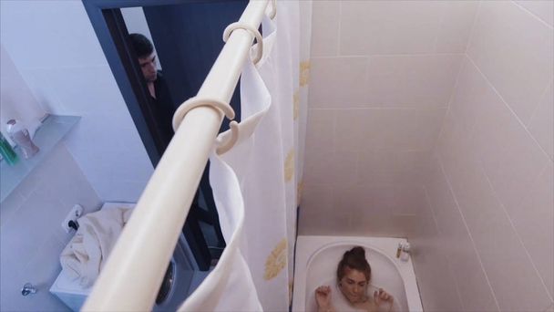 Kız banyo yaparken adam banyoya girer. Kız bir banyo alır ve kulaklıklar ile müzik dinlerken adam banyoda perde geri çeker. adam banyoda bir kız korkutuyor. - Fotoğraf, Görsel