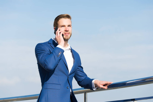 Man with smartphone on terrace on blue sky, business communication - Foto, Imagen