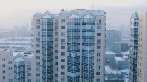 Πανόραμα της πολυκατοικίας με πτώση χιόνι σε πρώτο πλάνο. Χιόνι υπόβαθρο windows κτίσματα πολυόροφο κτίριο - Πλάνα, βίντεο