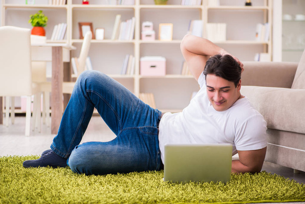 Man werkt op laptop thuis op tapijt vloer - Foto, afbeelding
