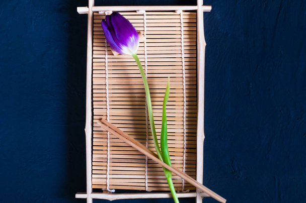 egy lila tulipán egy fa tálcán, sushi, konkrét kékre, felülnézet, hely a szöveg - Fotó, kép