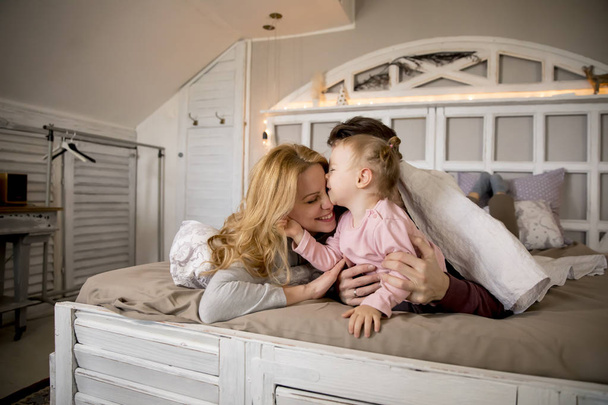 Pohled na mladou rodinu baví na posteli v ložnici - Fotografie, Obrázek