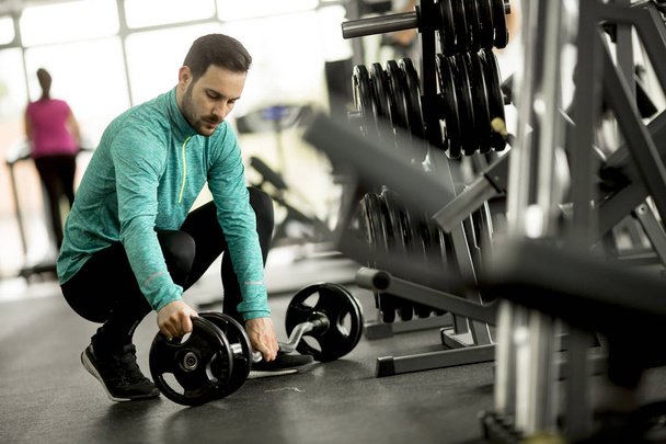Handsome young man prepares for the exercise in the gym - Photo, Image