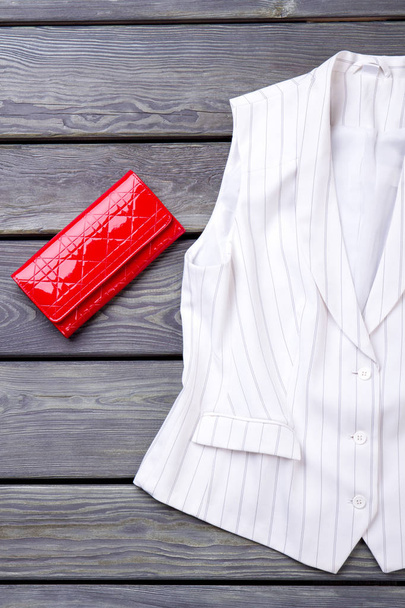 Червоний гаманець і біла куртка без рукавів
. - Фото, зображення