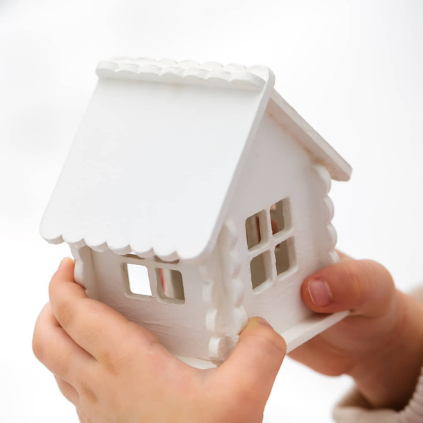 Child's hands is holding a toy house on a white background - Photo, Image