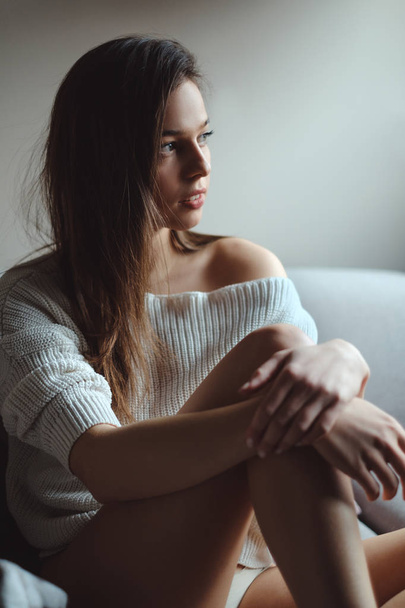 Сексуальная девушка в свитере и нижнем белье смотрит в сторону
 - Фото, изображение